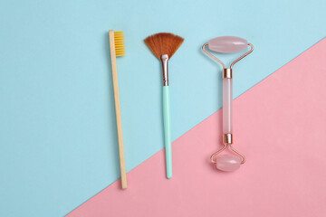 The concept of skin care and cleanliness of the oral cavity. Massage roller, makeup brush and a toothbrush on pink blue background