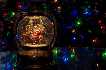 Santa in a blizzard inside snow globe with Christmas lights in the background