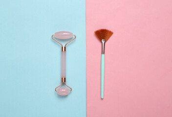 Massage roller and makeup brush on blue pink pastel background