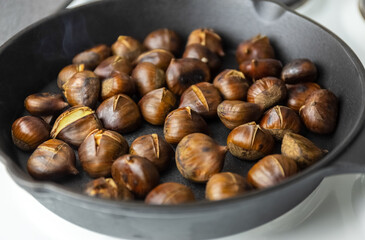 Ripe chestnuts are fried in a pan. the process of cooking chestnuts. Delicious delicacy. Photo