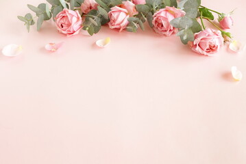Flowers background.Pink roses  and eucalyptus branch bouquet frame top view on pink background with copy space.  Poster