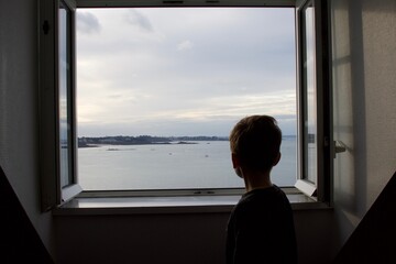 Fototapeta premium A child looking the sea by the window