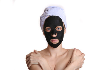 Beautiful woman with purifying black mask on her face and towel on head. Isolated on white background