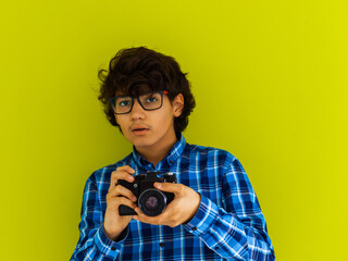 Enthusiastic arab teen photographer with analog slr camera on green background. Selective focus  - obrazy, fototapety, plakaty