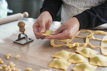 Woman working inside pasta factory while doing fresh made ravioli with vintage stamp