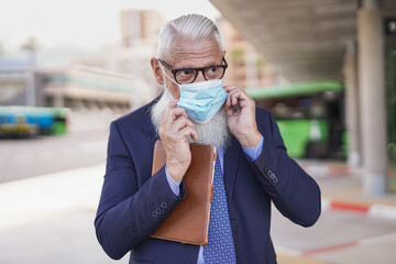 Business senior man wearing safety face mask for coronavirus outbreak while waiting on bus station