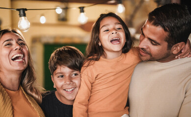Happy family laughing and hugging each other at home outdoor on patio - Latin parents with children...