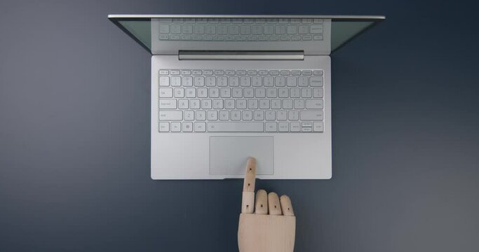 A wooden hand leads over the touchpad. Top view. Flat lay.