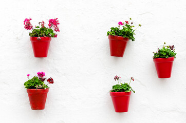 Fototapeta na wymiar Typical Andalusian white facade, with hanging red pots. Andalusian village, Marbella