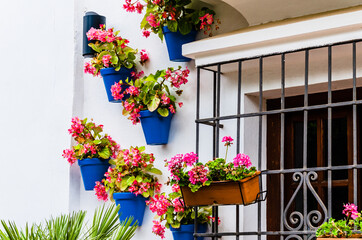 Fototapeta na wymiar Typical Andalusian white facade, with hanging blue pots, next to the window with bars. Andalusian village, Marbella