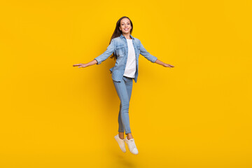 Fototapeta na wymiar Full size photo of young brown hair funky lady jump wear jeans shirt sneakers isolated on yellow color background