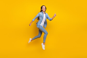 Full size profile photo of young pretty lady run wear jeans shirt footwear isolated on yellow color background