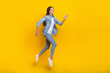 Fototapeta na wymiar Full length profile photo of mature good lady run wear jeans shirt footwear isolated on yellow color background