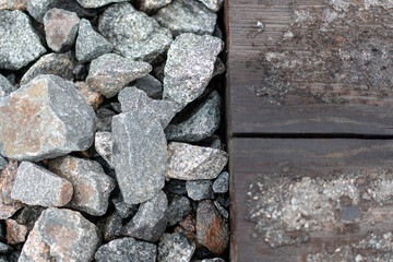 Photo of a large number of stones in different shades of gray and wooden boards. Abstract concept