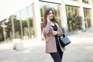 Stylish businesswoman talking on the phone in the city against the background of a business building