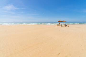 Fototapeta na wymiar Meer, blauer Himmel und zwei Sonnenschirme auf Sandstrand