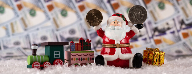 Ceramic figurine of Santa Claus holding in one hand 1 dollar coin, and in the other half a dollar against the background of dollar bills 