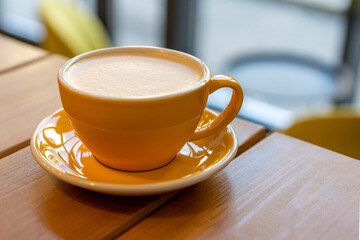 A cup of coffee in a yellow cup on wooden table. Cafe concept
