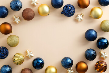 Frame made of colorful Christmas baubles on pastel beige background. Bronze, golden and blue...