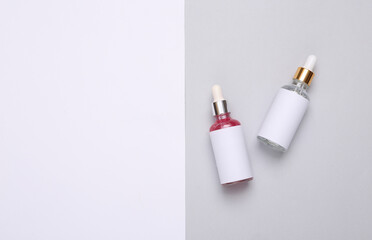 Face serum bottles with dropper on white gray background. Copy space