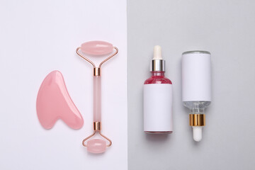 Beautiful composition of mockup serum bottles, pink face roller on gray white background. Creative trendy beauty flat lay