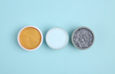 Jar of face cream, black clay and patches on a blue background. Beauty products, cosmetics. Top view