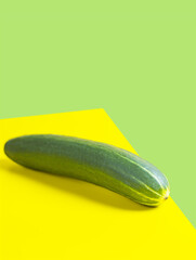 one whole long ripe green Cucumber isolated on yellow background. single cucumber