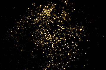Naklejka na ściany i meble Golden blurred bokeh lights on black background. Glitter sparkle stars for celebrate. Overlay for your design