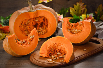  Whole fresh orange big pumpkin and slice of pumpkin on wooden board, closeup. Organic vegetable...
