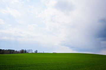 Selective focus photo. Dark clouds above agriculture field and hill.