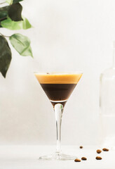 Espresso martini, trendy alcoholic cocktail with vodka, coffee liqueur, syrup and ice, black background, bar tools