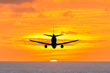 Sunset or sunrise (dawn, dusk ) flight of the airplane (jet) over beautiful sky and ocean.