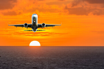 Sunset or sunrise (dawn, dusk ) flight of the airplane (jet) over beautiful sky and ocean.