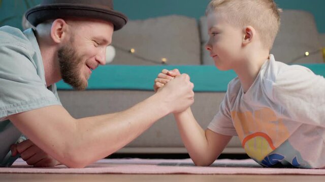 father and son are fighting with their hands. who is stronger. old and young. father and son play arm wrestling