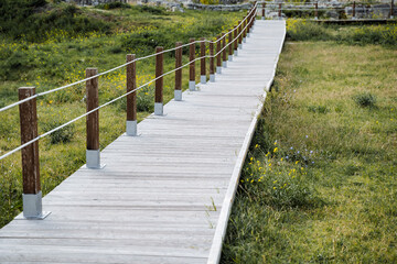 Fototapeta premium Wooden descent. Straight forward descent of white wood. Pleasant street interior. Stone fence at the coastal edge.