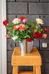 A bucket with a freshly cut bouquet of roses in the interior of an apartment or restaurant