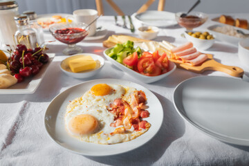 fried eggs with strips of juicy and fatty bacon on a plate during breakfast in a cafe or at home