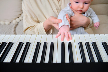 Woman musician with child teaches music on electronic piano at home