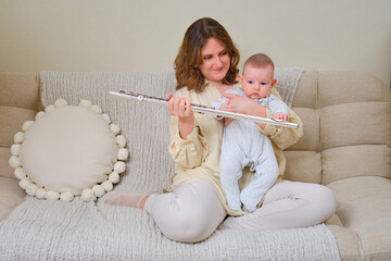 Woman musician with infant baby teaches music and shows the flute