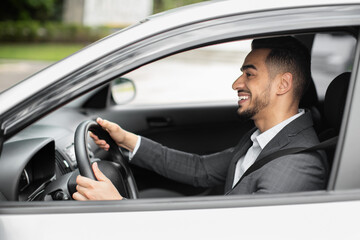 Happy middle eastern businessman driving his new auto, panorama