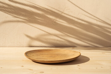 Podium, plate or bowl on wooden table on stucco background with natural shadow on the wall. Mock up...