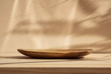 Podium or bowl on wooden table on stucco background with branch shadow on the wall. Mock up for...