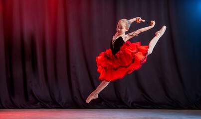 little ballerina girl dances on stage in ballet tutu on pointe shoes with castaned shoes, froze in...
