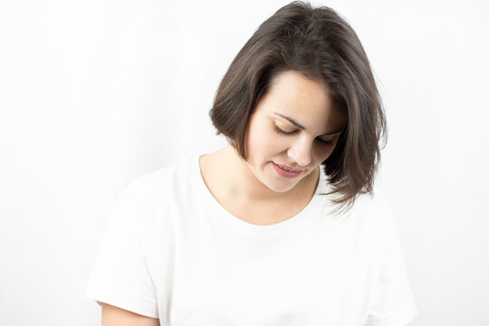 Studio photo of a young sad girl in a white T-shirt on a white background.
