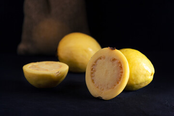 Yellow guava on black background, still life style. Healthy diet