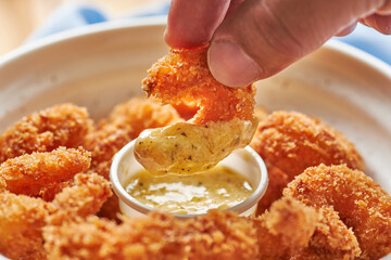 MANO DE HOMBRE COGIENDO CAMARON APANADO EN SALSA