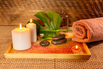 Spa, zen basalt stones, towels, candles on a wooden tray in the massage room.
