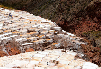 Maras salt terraces with silhouettes of Peruvian Quechua indigenous people doing salt harvest, Maras district, Cusco province, Peru.