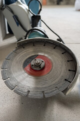 An angle grinder with a scratched stone disk lies on the concrete floor. Selective focus. The concept of room renovation.