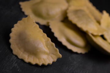 Tasty raw ravioli with flour and spinach on dark background, process of making italian ravioli, High quality photo
